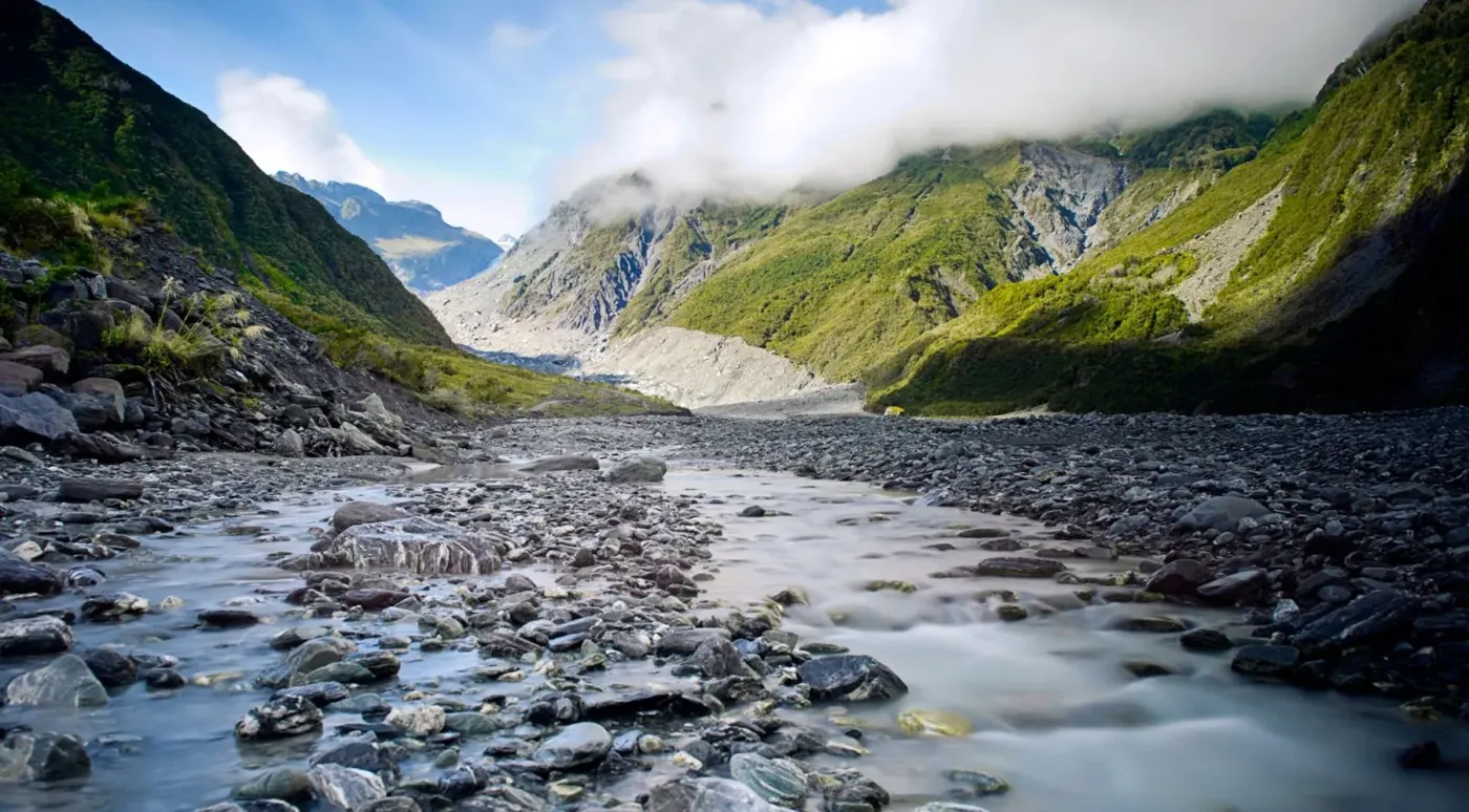 Glacier valley river below steep mountains