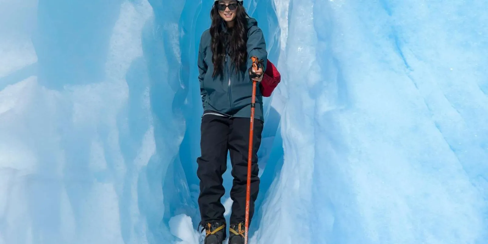 Hiker standing between blue glacier ice walls