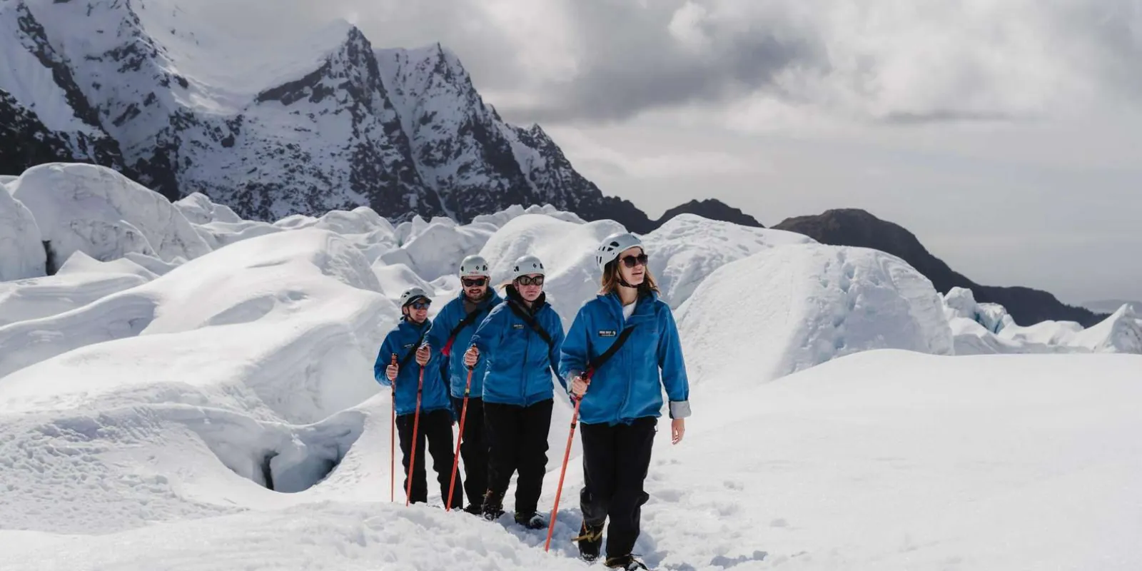 Hikers on open glacier ice beneath mountains