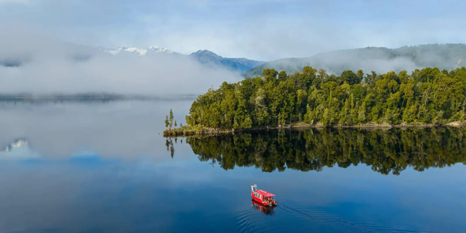 Small cruise boat beside rainforest islands